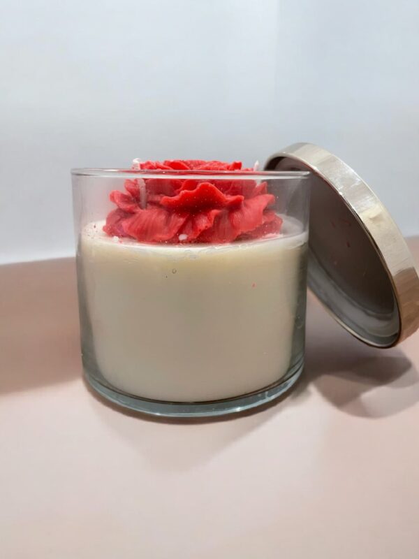 Decorative jar candle with a rose-shaped wax topper and soy wax base in a clear glass jar with a metallic lid.