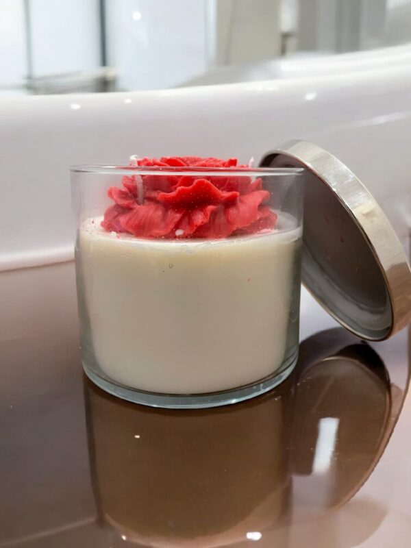 Decorative jar candle with a rose-shaped wax topper and soy wax base in a clear glass jar with a metallic lid.