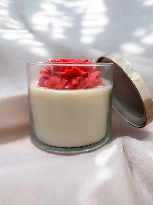 Decorative jar candle with a rose-shaped wax topper and soy wax base in a clear glass jar with a metallic lid.