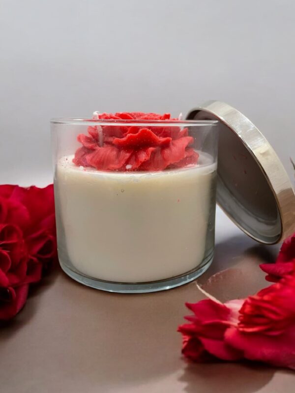 Decorative jar candle with a rose-shaped wax topper and soy wax base in a clear glass jar with a metallic lid.